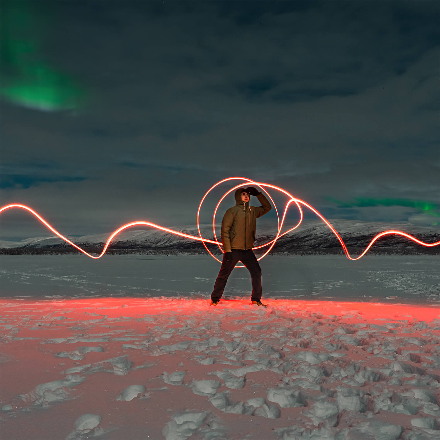 A person light-painting while waiting for the Northern Lights